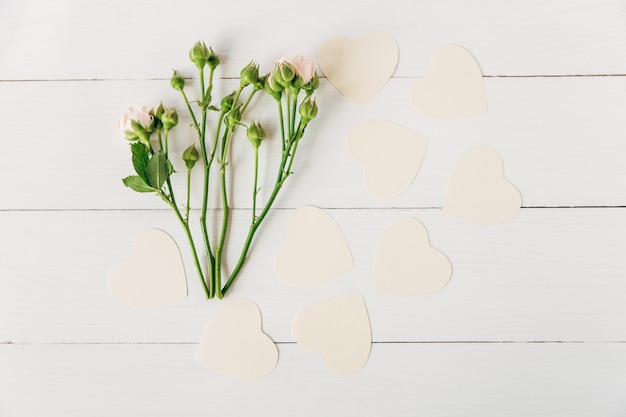 Corações de papel artesanal e fundo de madeira branco de flores plano plano