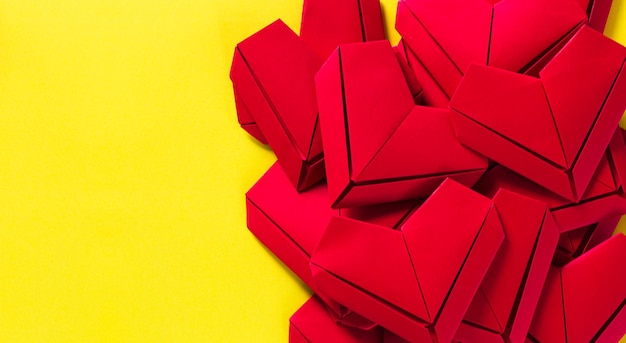 corações de papel em um fundo amarelo o conceito de amor no dia de São Valentim origami vermelho
