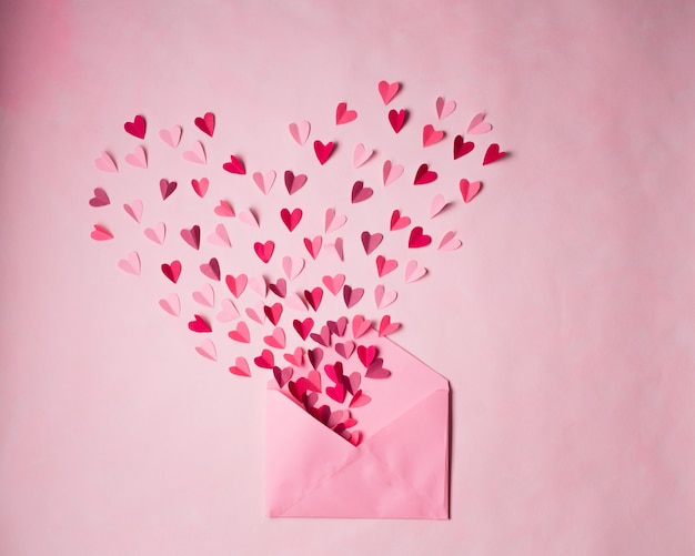 Corações de papel vermelho e rosa em envelope postal rosa aberto em rosa
