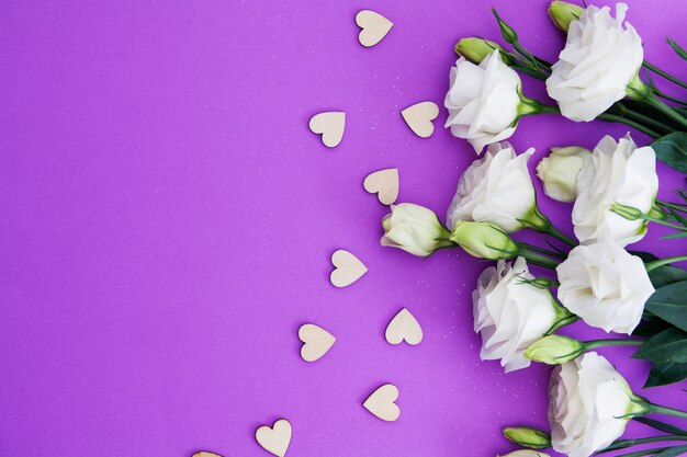 Corações e flores de madeira em um fundo roxo com um espaço da cópia para o texto. dia dos namorados, casamento, conceito de amor