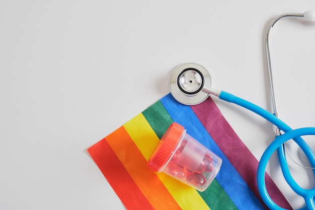 Corações em um banco de teste, estetoscópio médico e bandeira da comunidade LGBTQ em um espaço de cópia de fundo cinza, doação de espermatozoides e óvulos para casais gays, inseminação artificial, barriga de aluguel