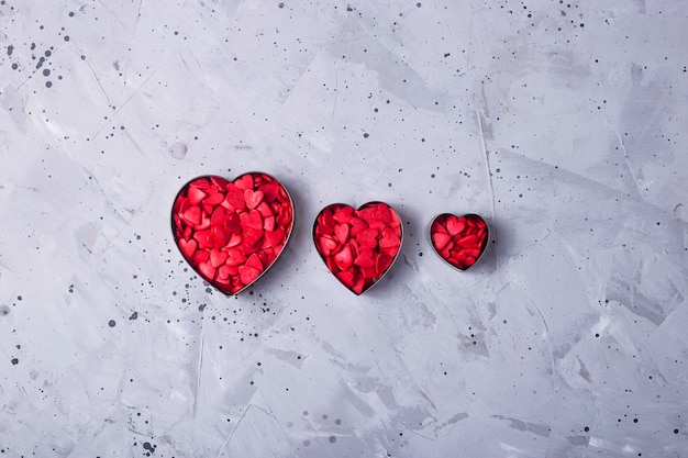 Corações pequenas vermelhas sobre uma mesa cinza como um símbolo de amor no Dia dos Namorados