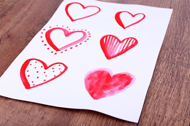 Foto corações pintados na folha de papel no fundo da mesa de madeira
