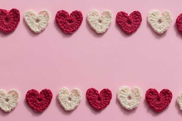 Corações vermelhos e brancos amigurumi de crochê em um fundo rosa Bandeira padrão do dia dos namorados