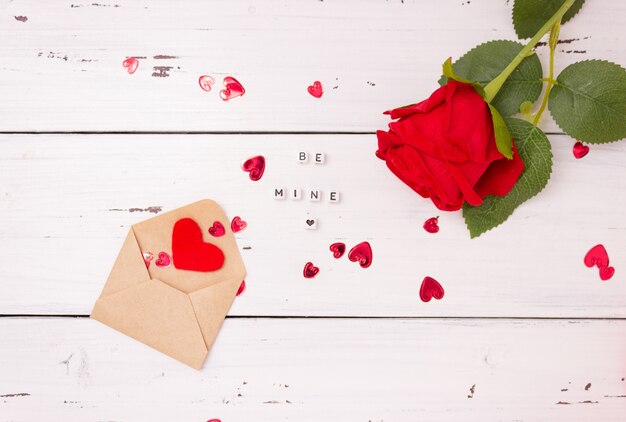 Corações vermelhos, envelope de carta aberta feito de papel kraft e uma rosa