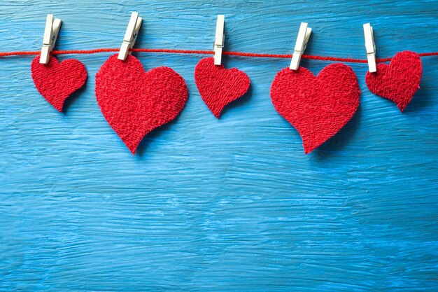 Foto corações vermelhos pendurados em um fio com pinças de roupa em um fundo azul claro