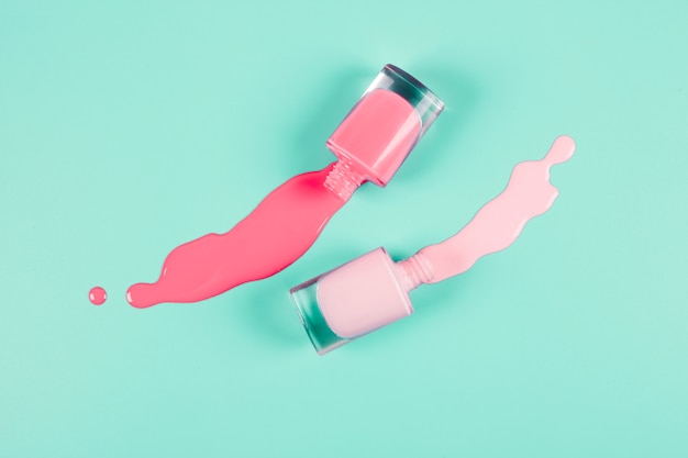 Corais e rosa derramado unha polonês garrafas em fundo de hortelã
