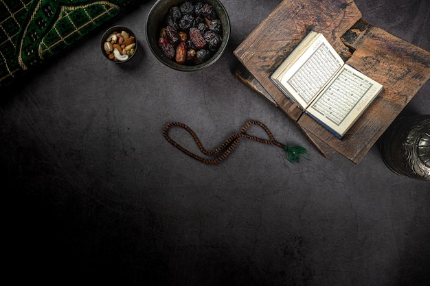 Corán abierto cerca del concepto de fechas de ramadan kareem sobre fondo de textura oscura