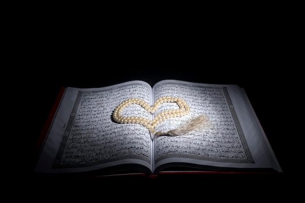 Corán abierto con cuentas de oración con fondo oscuro