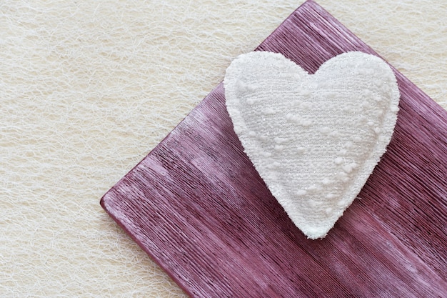 Foto corazón blanco hecho de tela. juguete de peluche con forma de corazón sobre madera.