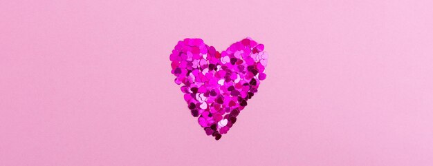 Corazón brillante de destellos en forma de corazones sobre un fondo rosa El concepto de día de San Valentín, amor, citas y bodas, espacio de copia, banner web