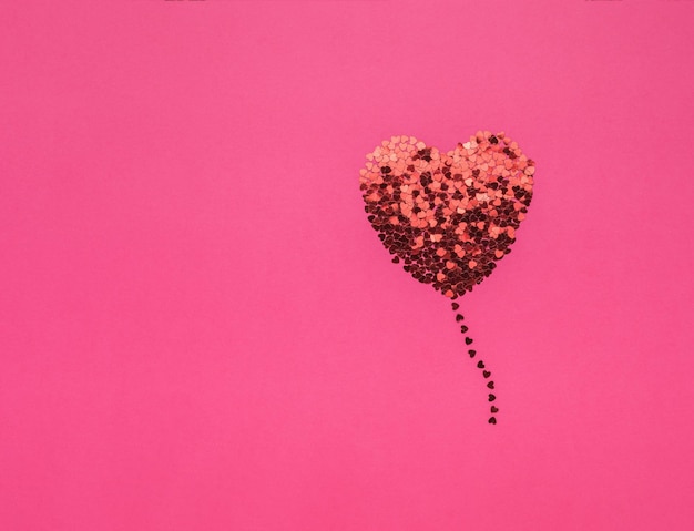 Un corazón brillante en forma de globo y un lugar para el texto sobre un fondo rosa. El concepto de San Valentín.