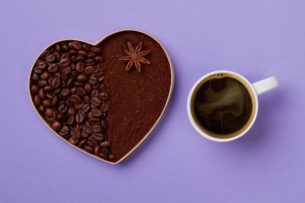 Corazón de café decorativo y taza de café. Granos de café y café instantáneo con anís sobre superficie violeta.