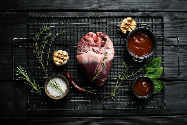 El corazón de cerdo crudo está listo para cocinar con especias y hierbas Carne sobre un fondo negro