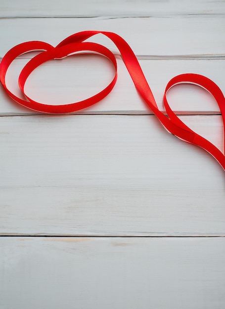 Corazón de cinta roja sobre un fondo de madera blanca en una familia o boda romántica del día de San Valentín