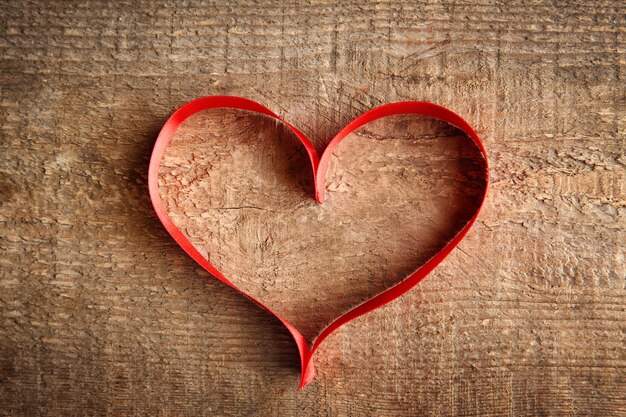 Corazón de cinta roja sobre fondo de madera