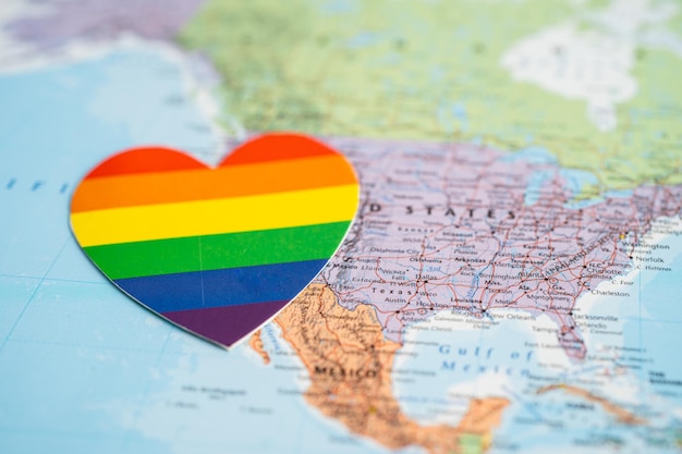 Corazón de color del arco iris en el símbolo de fondo del mapa mundial del mes del orgullo LGBT