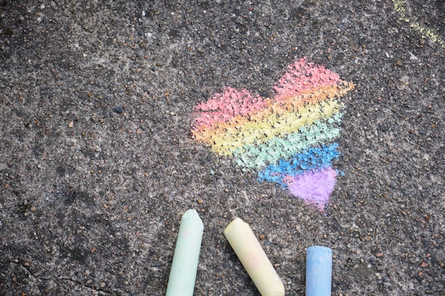 El corazón de color arcoíris se dibuja con tiza en el asfalto.