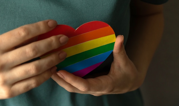 Corazón en colores del arco iris LGBT en manos. Foto de fondo del mes del orgullo y la tolerancia.