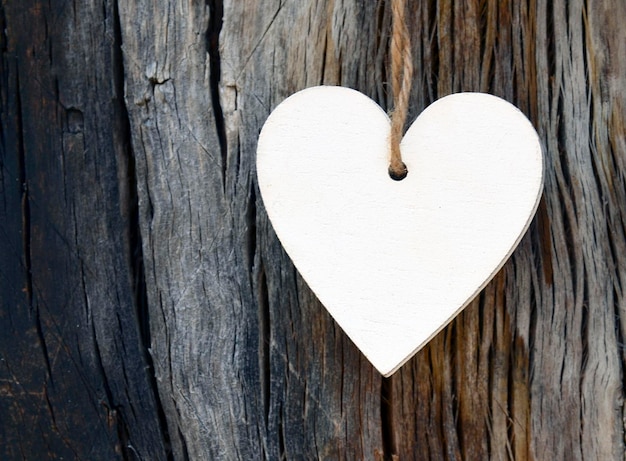 Corazón decorativo de madera blanca sobre fondo de madera antiguo con espacio de copia