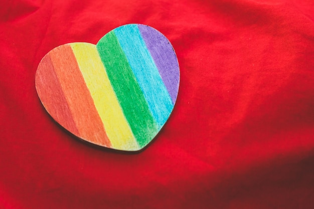 Corazón decorativo con rayas de arco iris sobre fondo rojo. bandera del orgullo lgbt, símbolo de lesbiana, gay, bisexual, transgénero.