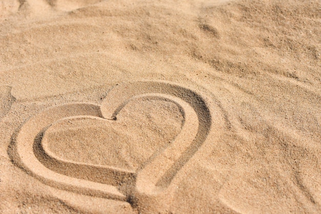 Corazón dibujado a mano en la arena de mar en la playa