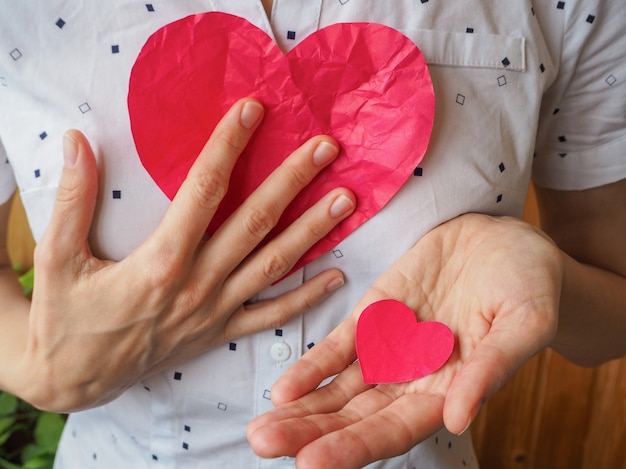 Corazón donado Corazón rojo grande y pequeño en su mano.