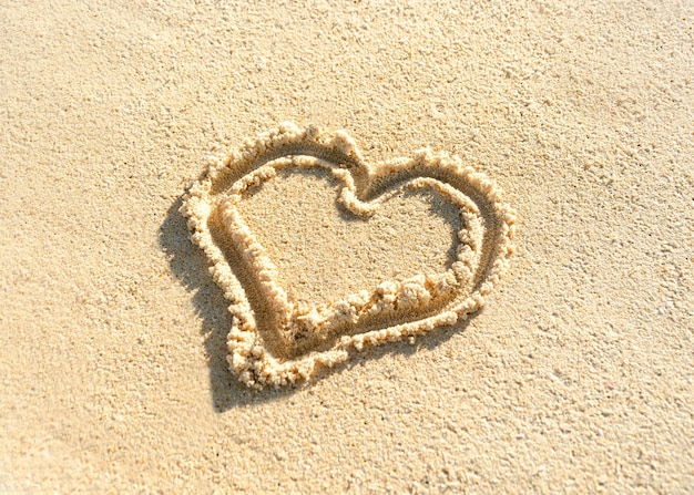 El corazón está dibujado en la arena de la playa Corazón pintado en la arena