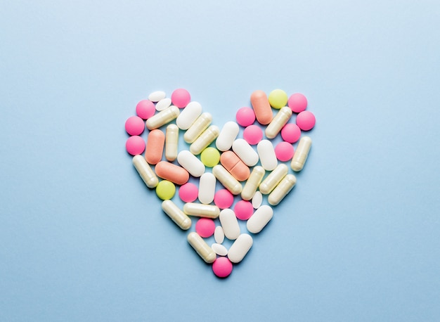 El corazón está dispuesto de pastillas sobre una mesa azul. Salud. Medicamento. Farmacia.