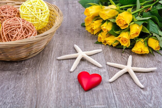 Foto corazón de estrella de mar y rosas en una mesa de madera