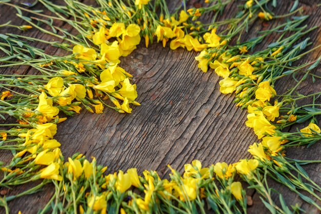 Corazón de flores amarillas sobre fondo de madera, concepto de amor y romance, espacio de copia