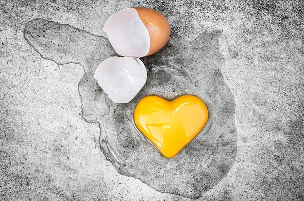 Corazón en forma de yema de huevo con cáscaras de huevo en el suelo. Día de San Valentín