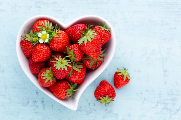 Corazón de fresa. Fresas frescas en placa sobre mesa de madera blanca. Vista superior, copie el espacio.