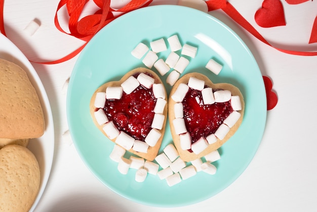 Corazón de galleta decorado con mermelada y malvaviscos para el día de San Valentín, primer plano, horneado para las vacaciones. vista superior de corazones decorativos.