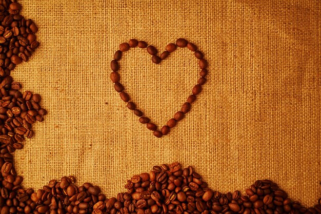 Corazón de grano de café sobre fondo de saqueo