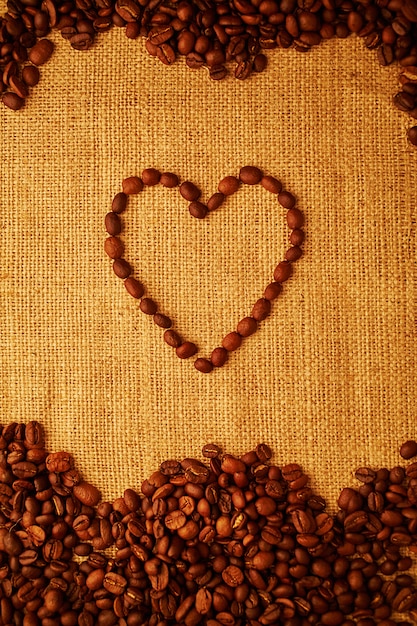 Corazón de grano de café sobre fondo de saqueo