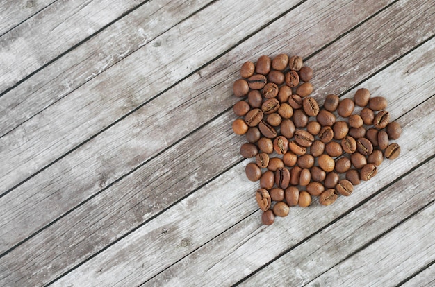 Corazón de granos de café sobre un fondo de madera