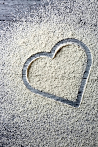 Corazón de harina sobre fondo de madera