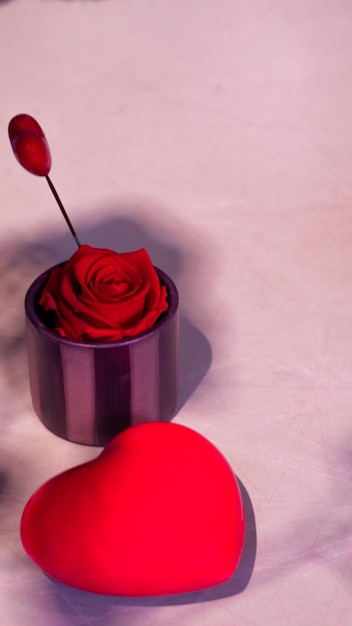 Corazón hecho de chocolate con un pequeño jarrón que contiene una rosa roja y un pequeño producto de espacio de copia de corazón