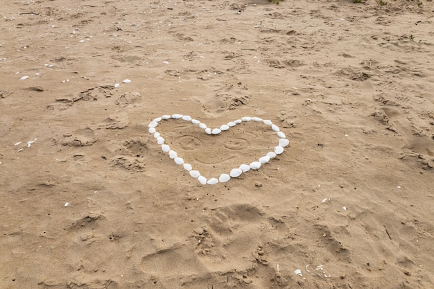 Corazón hecho de conchas marinas en la playa del mar. Concepto de amor de vacaciones