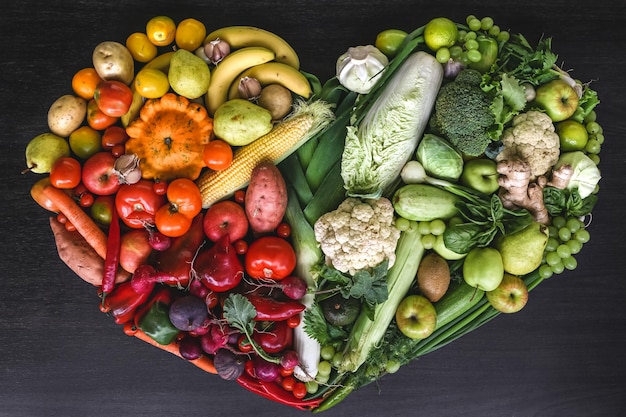 Corazón hecho de frutas y verduras frescas sobre fondo de madera