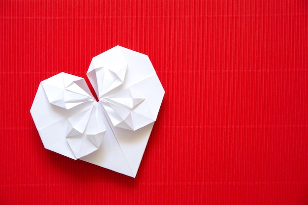 Corazón hecho de origami de papel sobre fondo de cartón rojo para el día de San Valentín