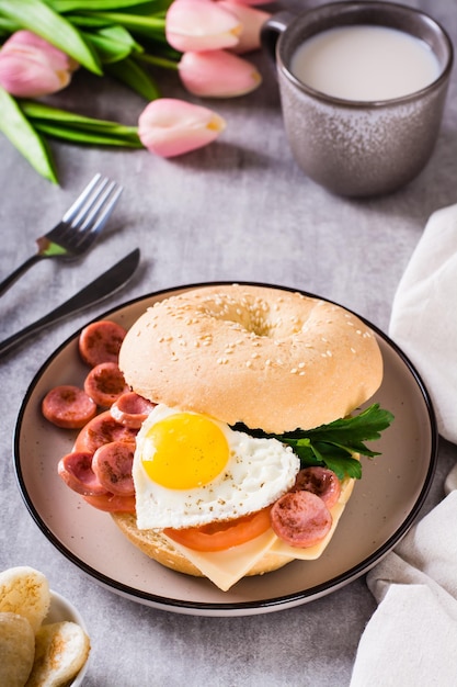 Corazón de huevo frito tomates queso y perejil en un bagel en un plato Desayuno romántico