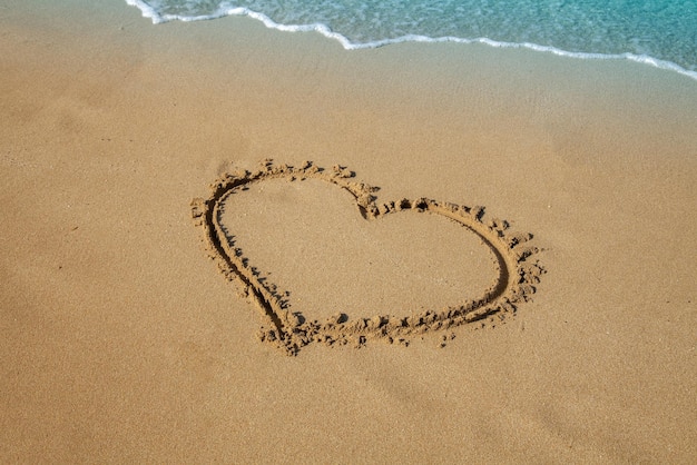 Corazón de inscripción en la arena de la playa