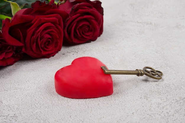 Corazón, una llave y un ramo de rosas sobre un fondo de mármol gris