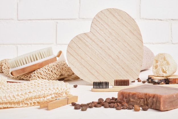 Corazón de madera y productos de higiene ecológicos para el cuidado y la higiene, accesorios de baño hechos de materiales naturales sobre una superficie beige, estilo de vida sin desperdicio