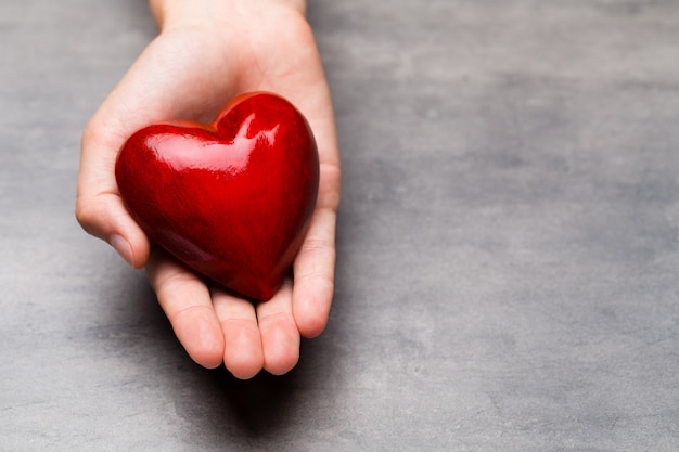 Corazón de madera roja en manos del niño.