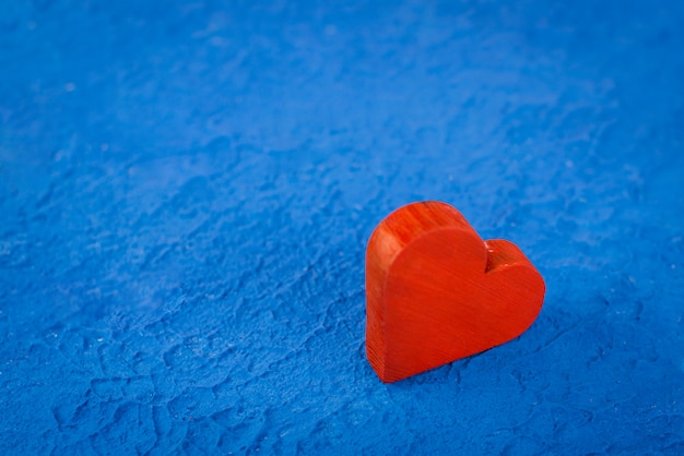 Corazón de madera roja sobre un fondo azul con textura. Concepto de amor y romance con espacio para texto. Abierto para Fondos de San Valentín para tu escritorio.