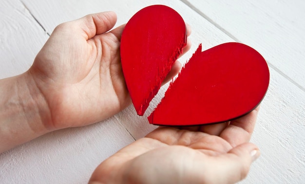 El corazón de madera rojo roto en manos de mujer