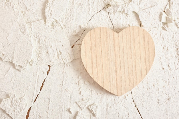 Corazón de madera sobre fondo de arcilla de textura agrietada simulacro de fondo para la presentación del producto